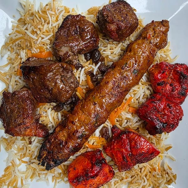 Khorasan Kabab's Afghan platter with various grilled meats, including a long kabob, on a bed of rice.